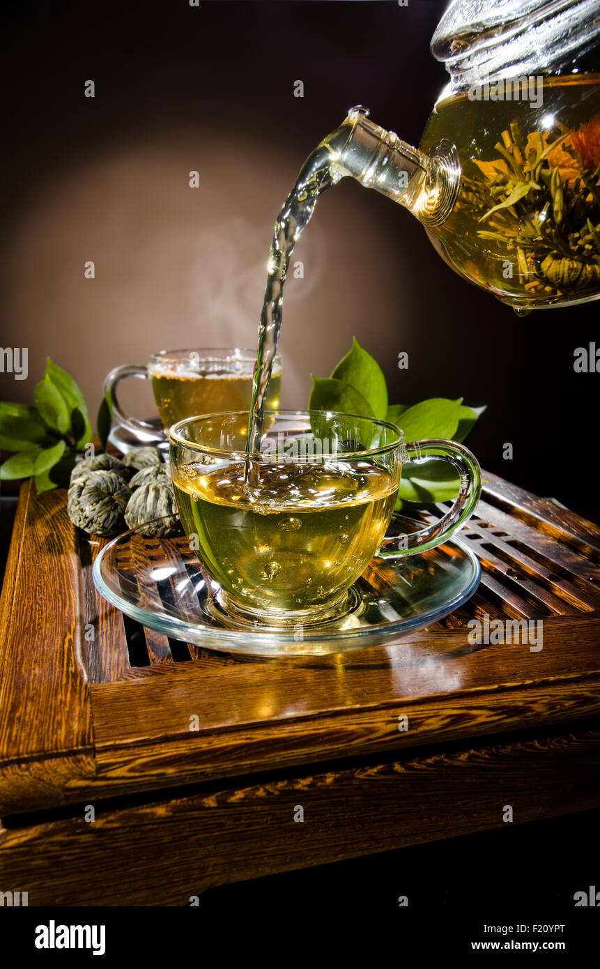 Photo verticale, de la théière en verre tasse thé vert en débit sur fond brun, cérémonie du thé Banque D'Images
