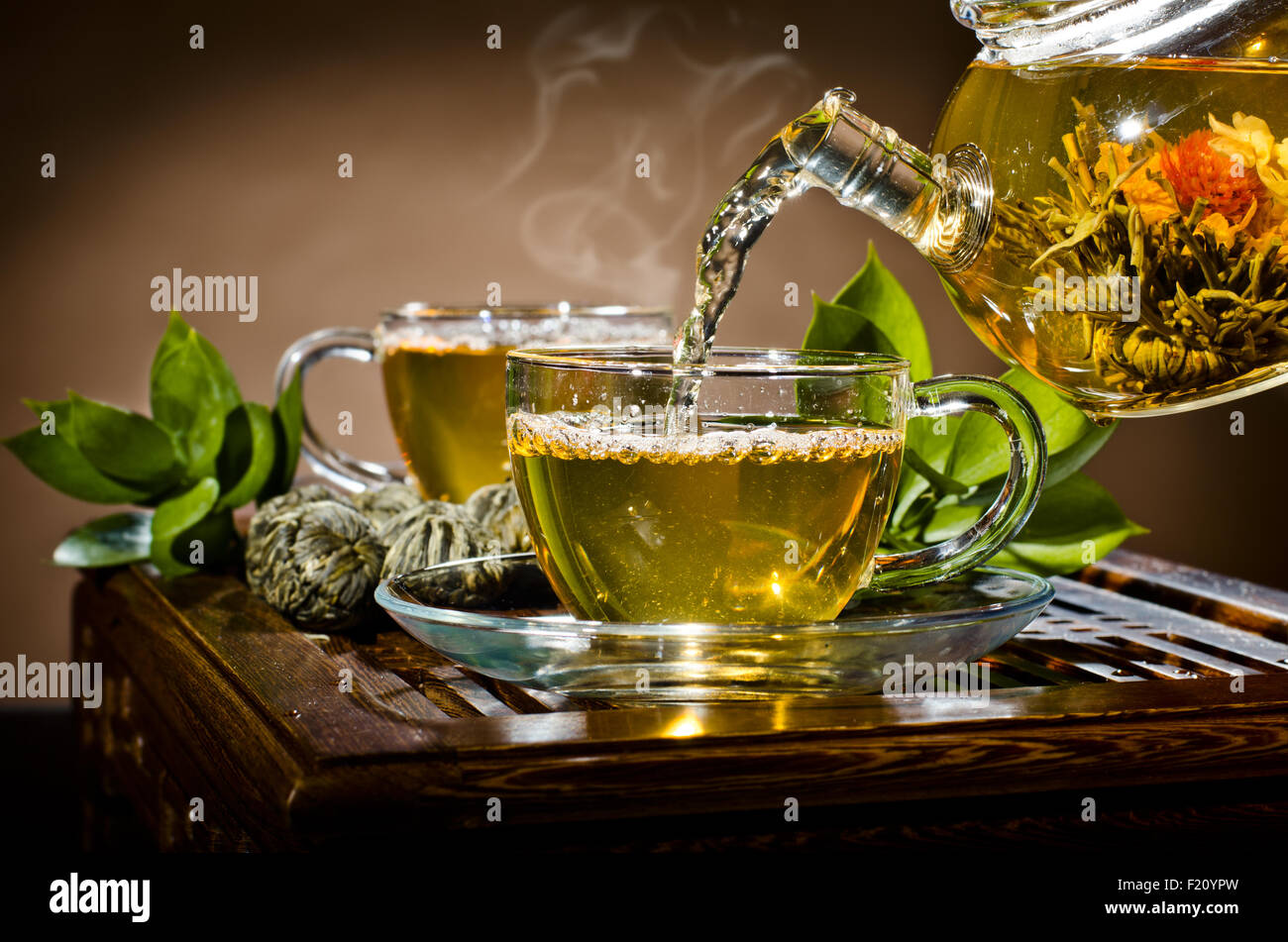 Photo horizontale, de la théière en verre tasse thé vert en débit sur fond brun, cérémonie du thé Banque D'Images