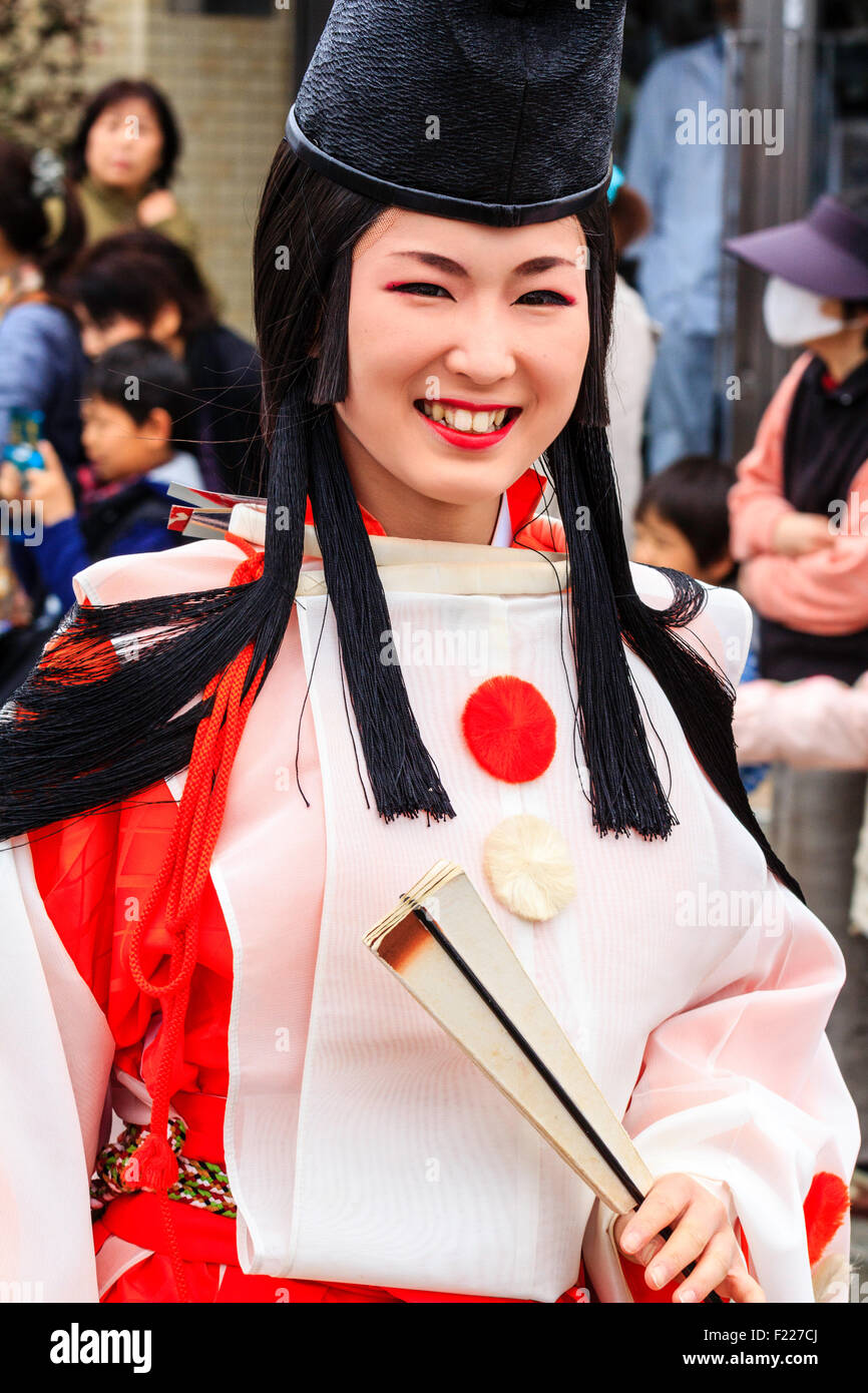 Défilé du festival de Genji, Japon. Tada Jeune femme habillée en danseuse shirabyoshi Heian, avec une longue jupe rouge, chemisier blanc, et grand chapeau noir. En souriant. Banque D'Images