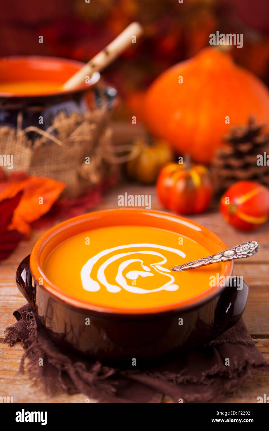 Un bol de soupe au potiron crémeuse faite maison sur une table rustique avec des décorations d'automne. Banque D'Images
