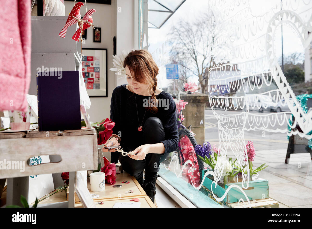 Une femme mature dans une boutique de cadeaux par la fenêtre, tenant une petite étoile. Banque D'Images