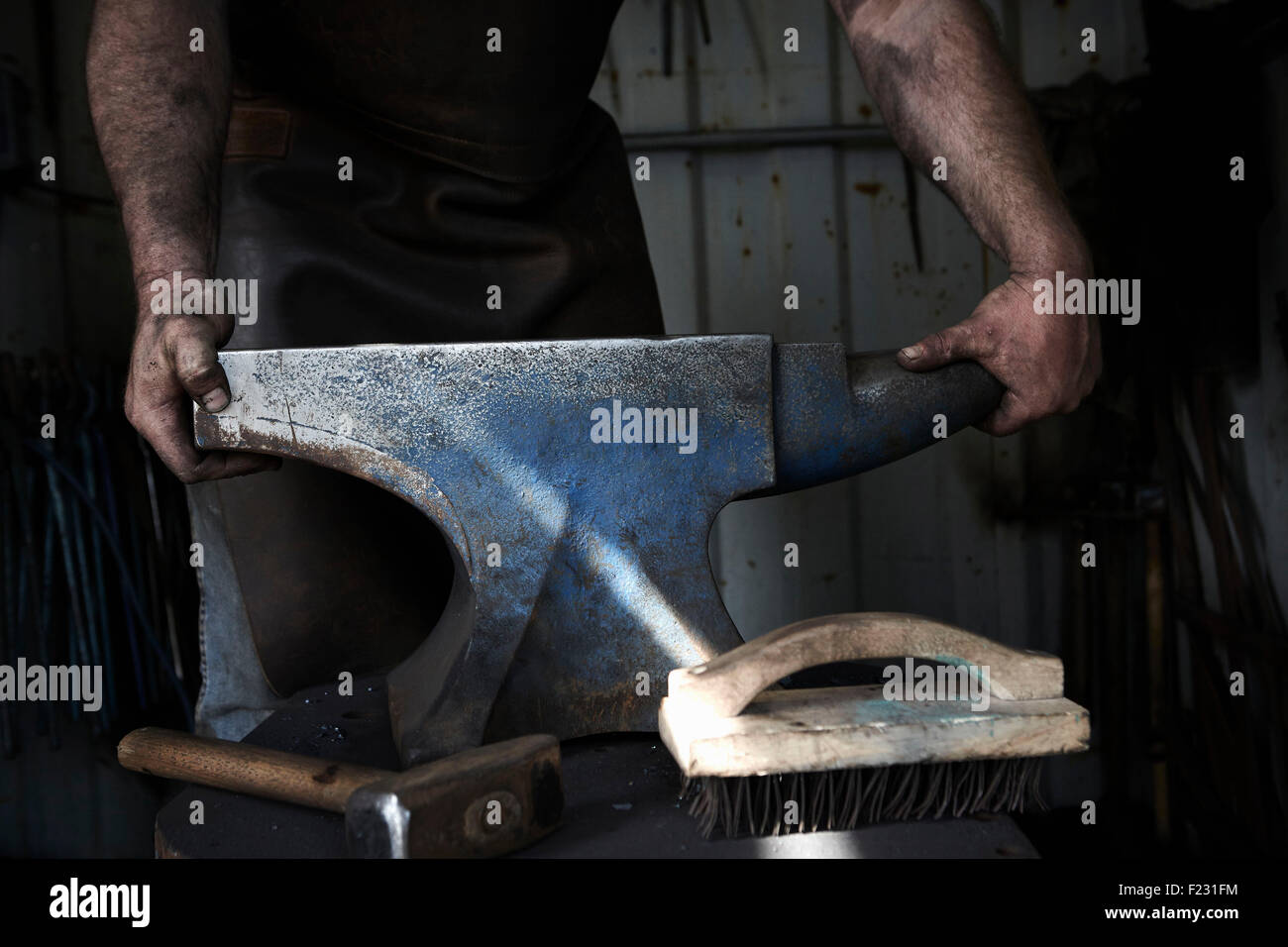 Blacksmith debout à une enclume dans une forge traditionnelle. Banque D'Images