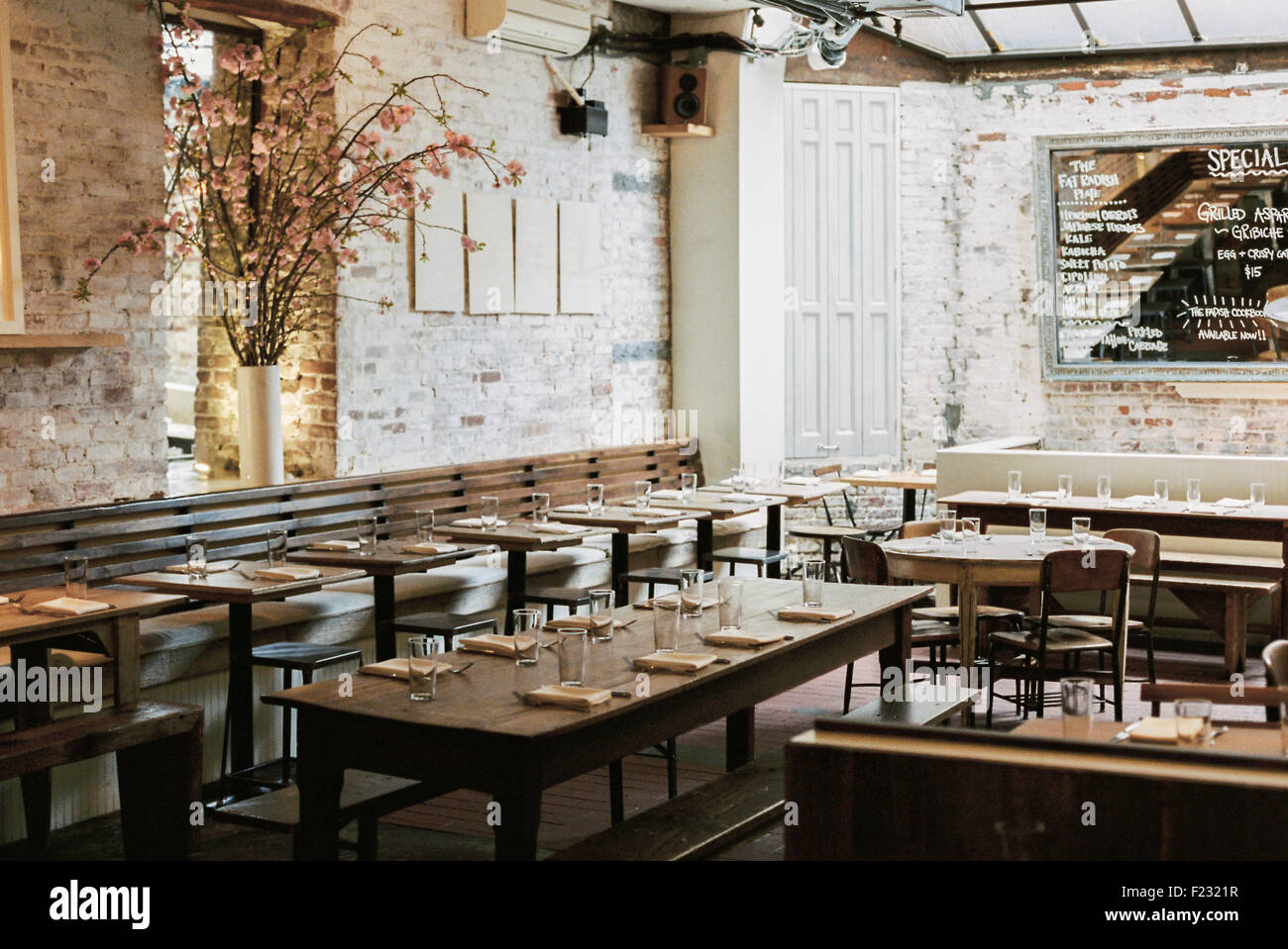 Un restaurant avec tables et chaises longues et étroites fixées pour un repas. Un grand menu chalk board. Banque D'Images