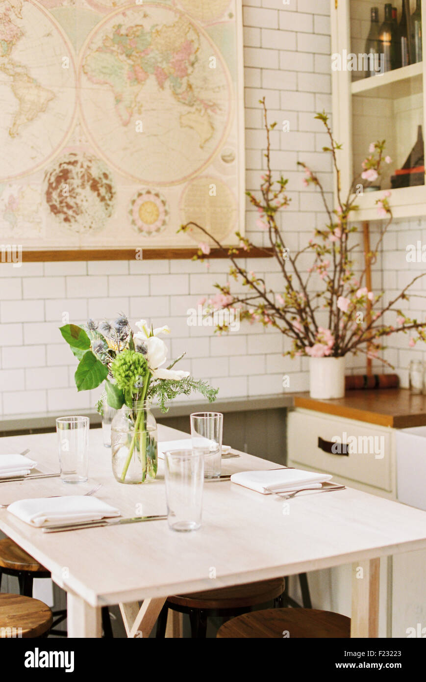 Une petite table avec quatre couverts et de fleurs dans un pot. Banque D'Images