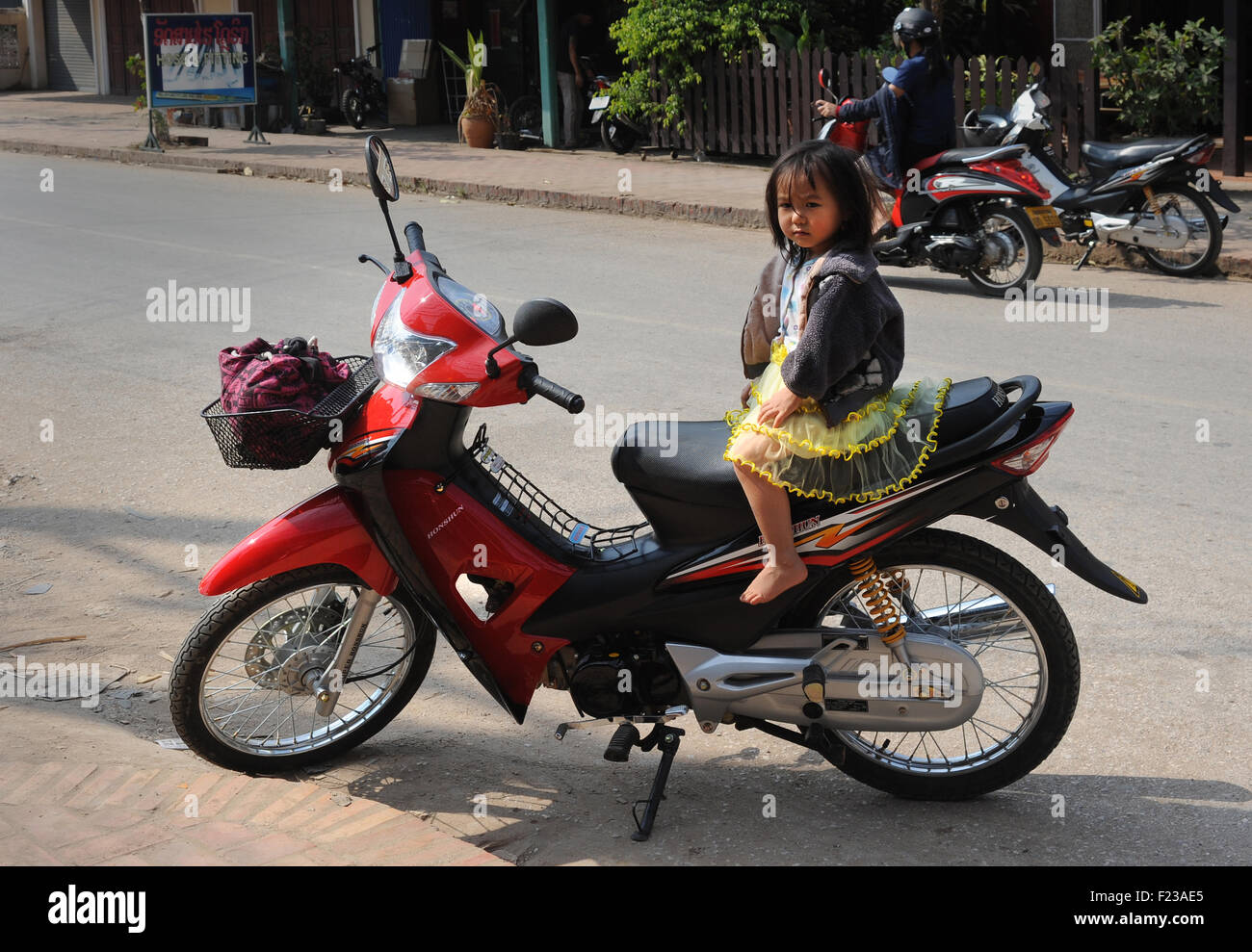 Jeune fille assise seule sur une moto. Luang Prabang, Laos Banque D'Images