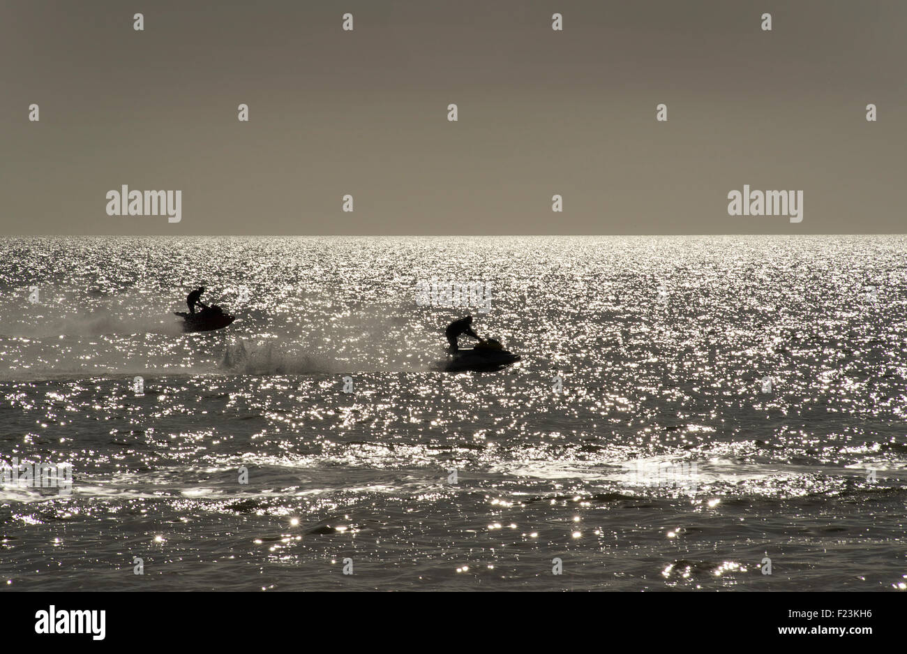 Jet-ski au large de la plage de Brighton. Silhouettes dans une mer étincelant Banque D'Images