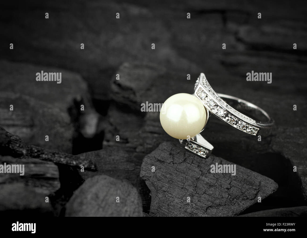 Bijoux avec perle et brillant foncé sur fond de charbon, soft focus Banque D'Images