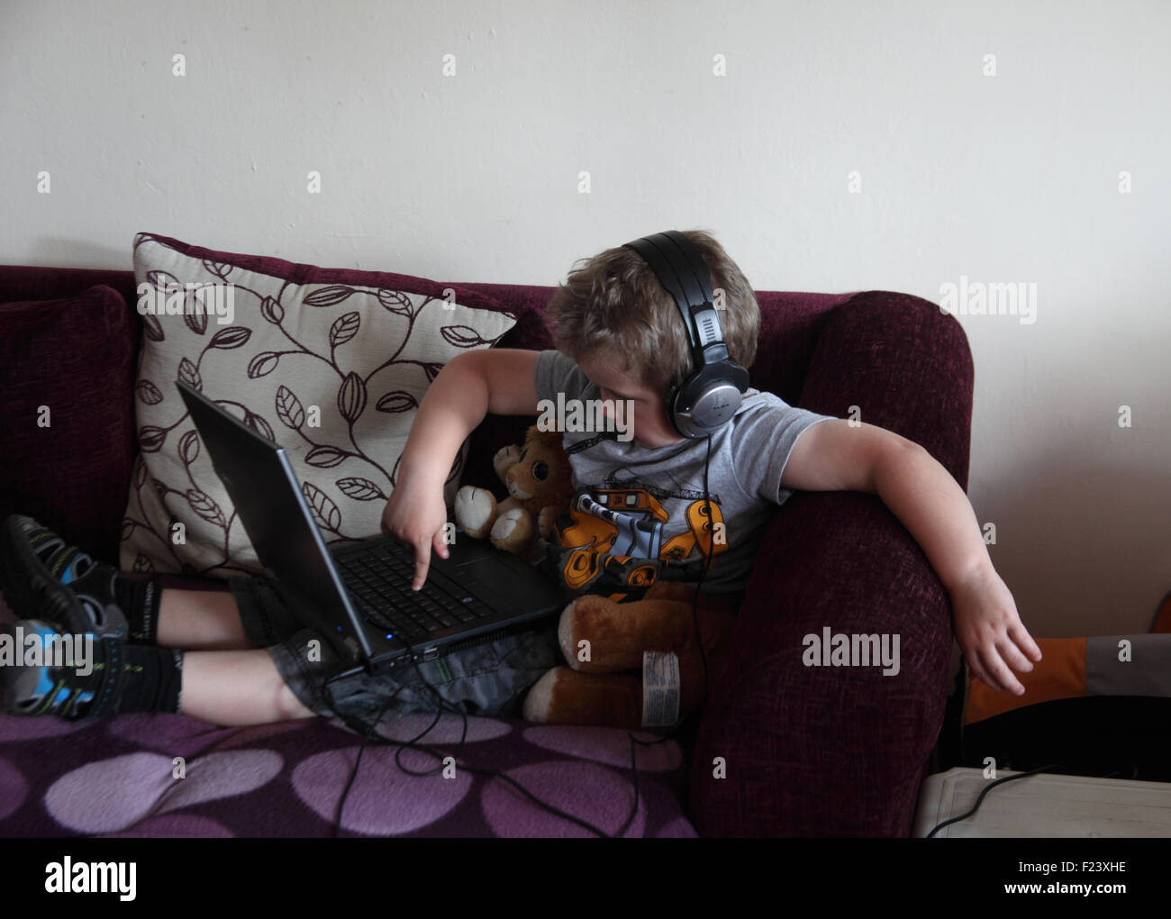 Petit garçon regardant la vidéo sur un ordinateur portable avec des écouteurs Banque D'Images