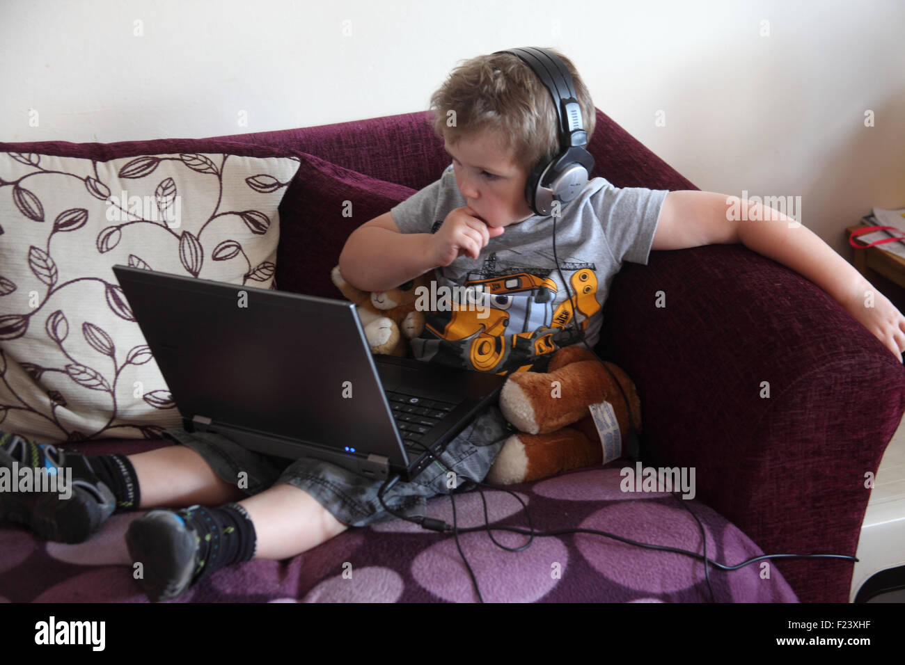 Petit garçon regardant la vidéo sur un ordinateur portable avec des écouteurs Banque D'Images