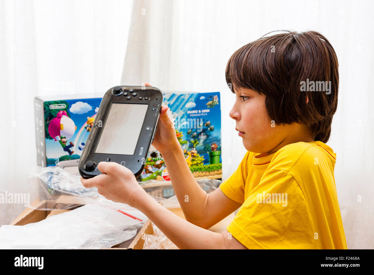 Homme de race blanche enfant, garçon, 11-13 ans, tenant à deux mains une  console Nintendo Wii U juste après avoir sortie de la boîte, qui est à côté  de lui Photo Stock -