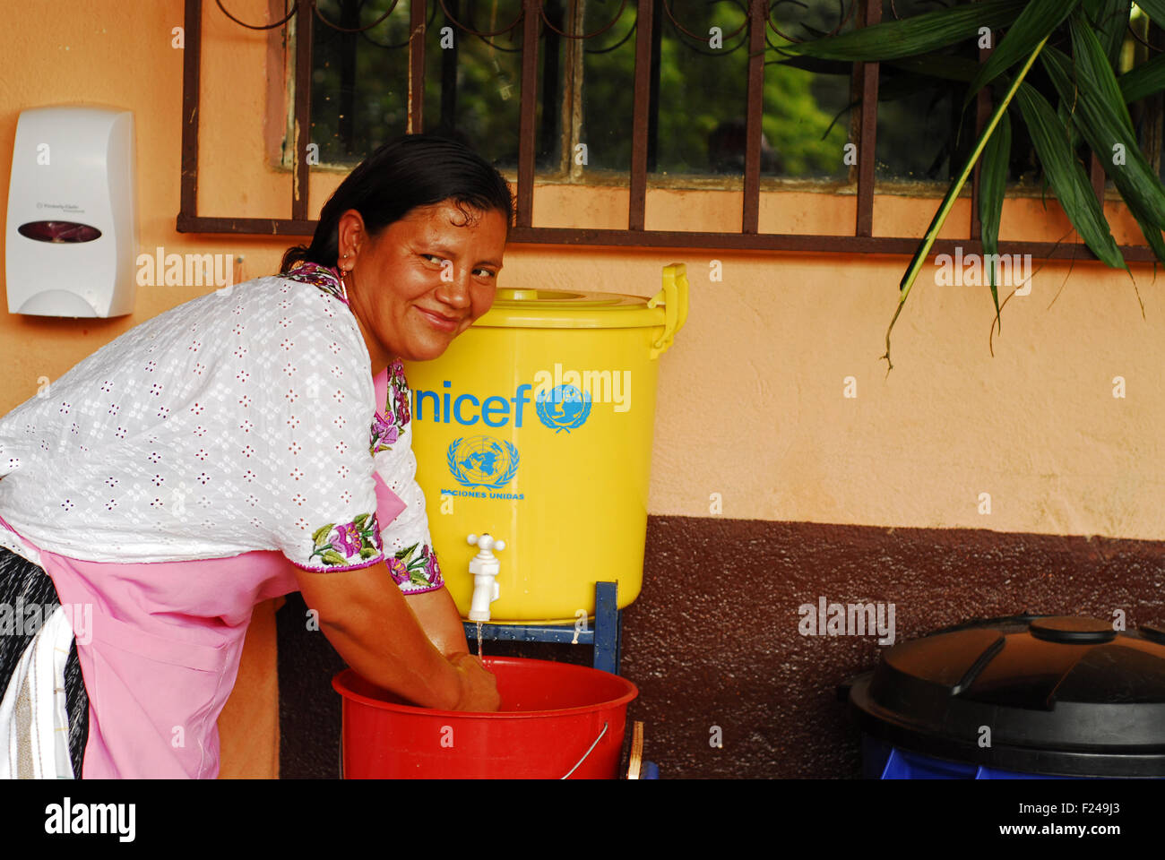 Guatemala, San Juan Chamulco, mère de l'école ( Ana Lucia 26 Cacao) se laver les mains avant de préparer des aliments pour les enfants Banque D'Images