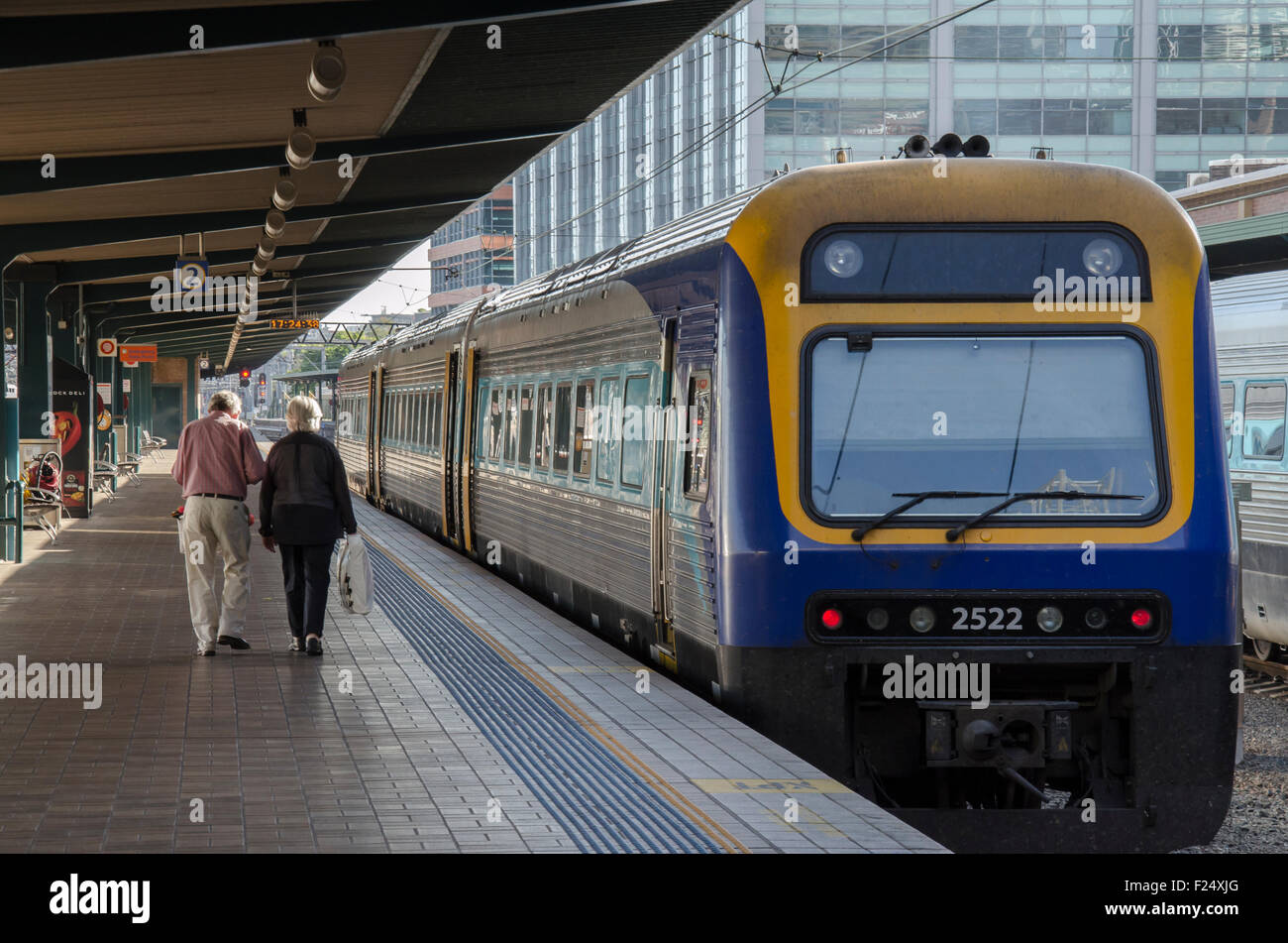 Deux personnes âgées descendent une plate-forme de chemin de fer vers un train d'attente.Le train est un service de locomotive de classe diesel Endeavour de Sydney. Banque D'Images