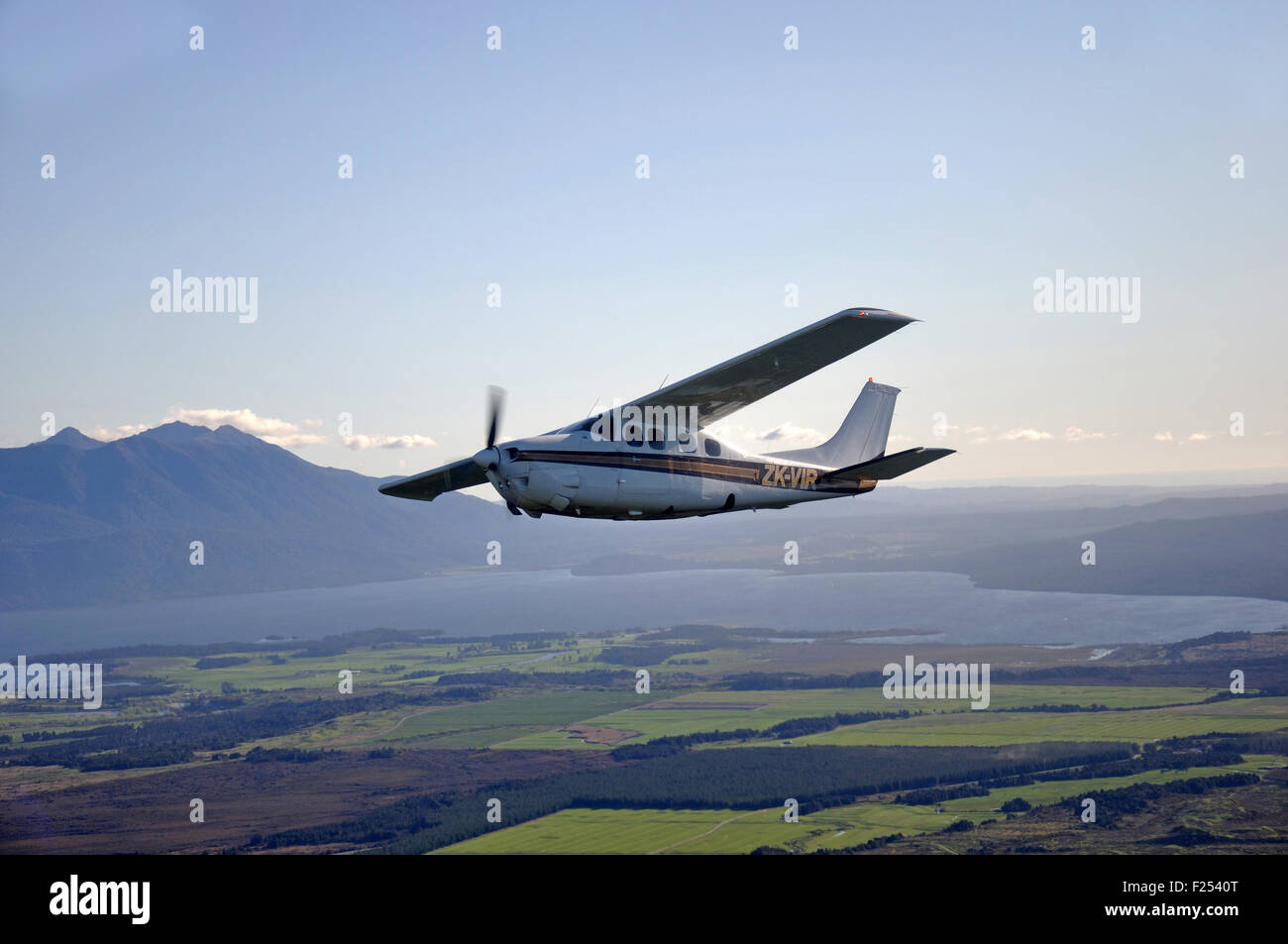 Un Cessna 210 sous pression vole au-dessus de la pittoresque côte ouest de la Nouvelle-Zélande Banque D'Images