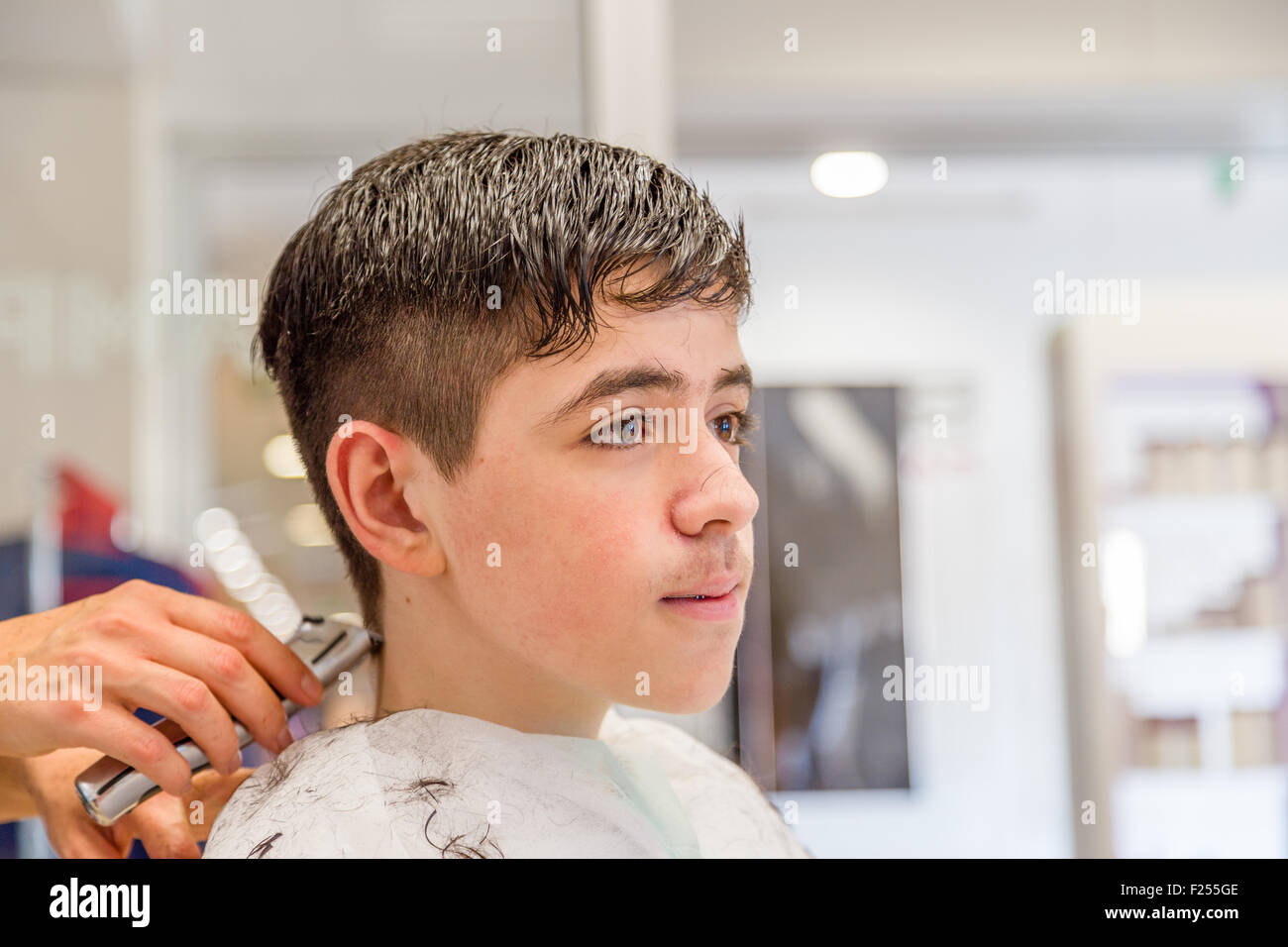 Cute caucasian teenage boy avec corset assis au salon de coiffure pour une coupe Banque D'Images