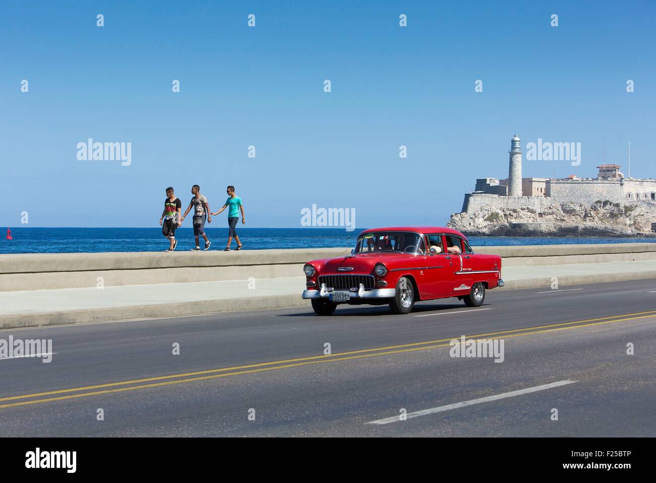 Cuba, Ciudad de la Habana Province, La Havane, voiture américaine sur le Malecon et le phare du Castillo de los Tres Reyes Magos dans l'arrière-plan Banque D'Images