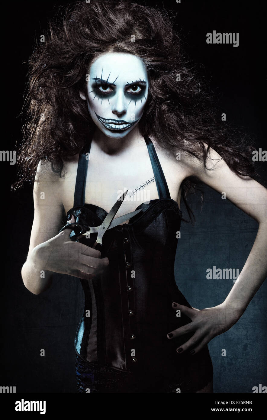 Jeune femme à l'image d'un gothique mal freak clown avec des ciseaux dans la main. Effet texture Grunge Banque D'Images