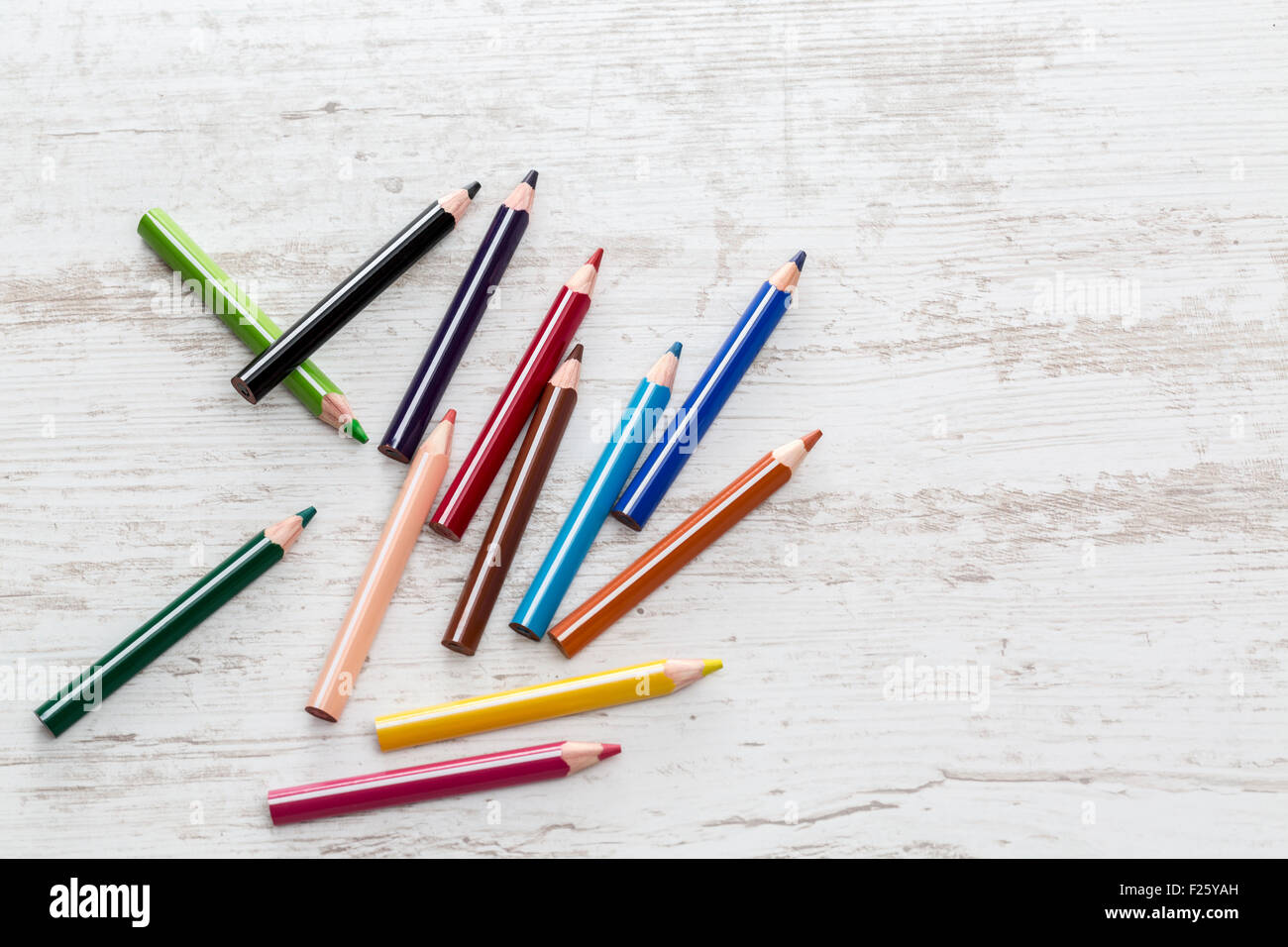 Vue de dessus d'un tas de crayons de couleur sur une table en bois blanc. Banque D'Images