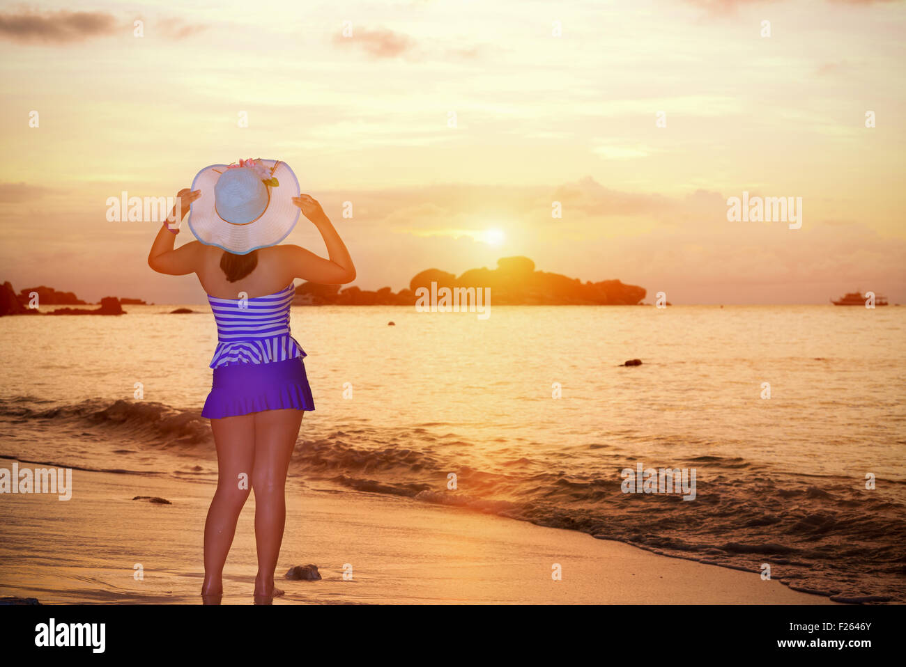 Les visiteurs femme dans un maillot bleu et hat standing looking du magnifique paysage de ciel au-dessus de la mer sur la plage heureusement Banque D'Images