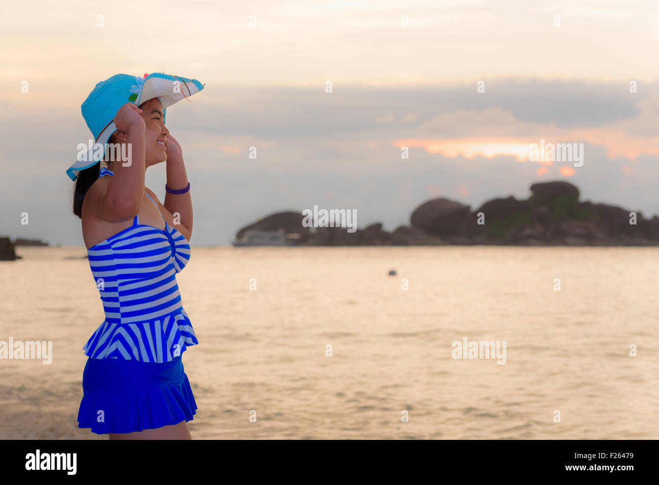 Les visiteurs femme dans un maillot bleu et hat standing looking du magnifique paysage de ciel au-dessus de la mer sur la plage heureusement Banque D'Images