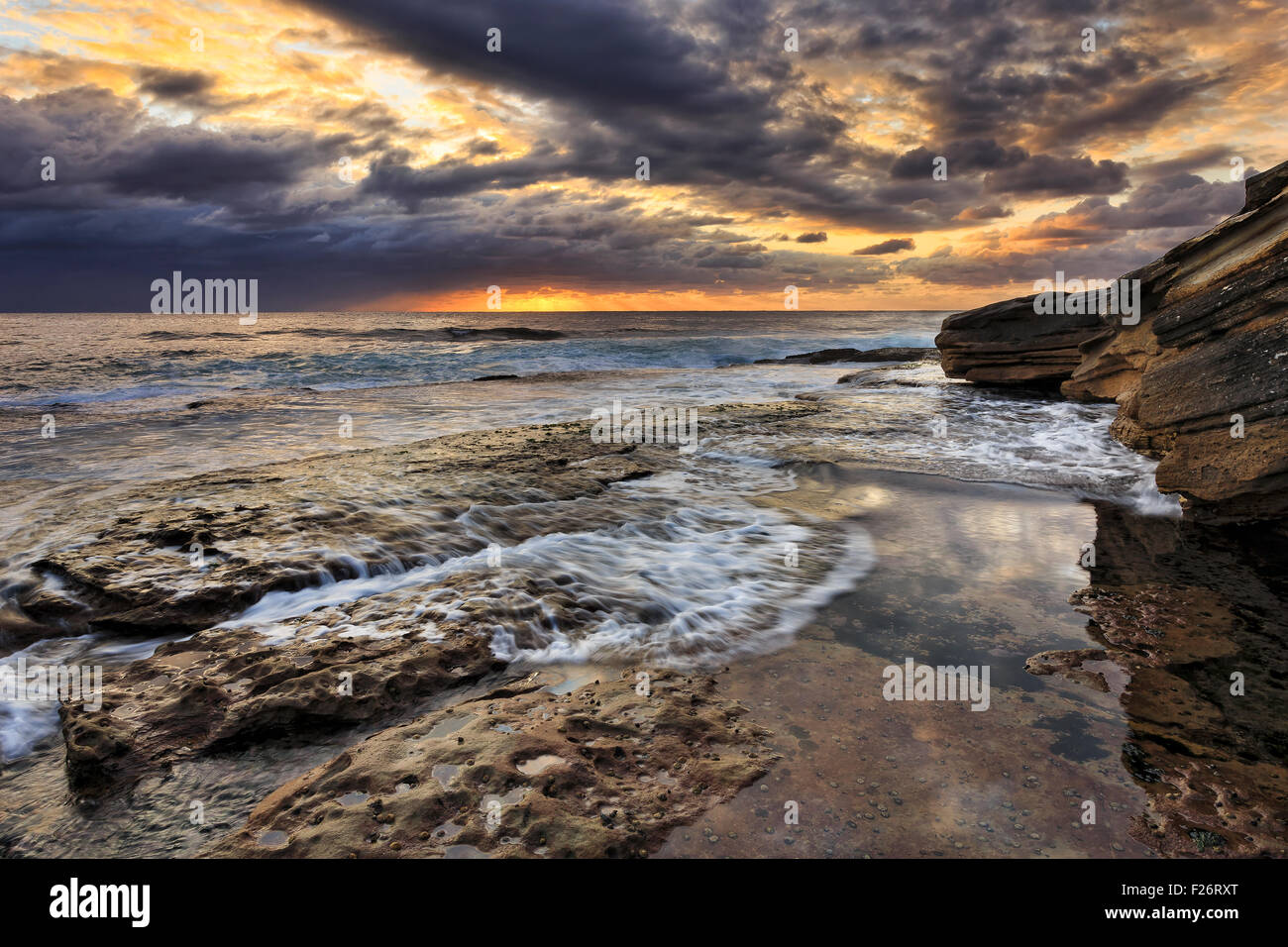 Flaque d'eau de mer toujours avec reflet de ciel d'orage au lever du soleil de la côte rocheuse du Pacifique Sydney Banque D'Images