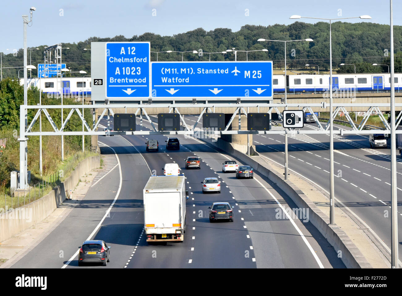 Infrastructure de transport pont ferroviaire et train de voyageurs TFL traversant la circulation routière à la sortie 28 de l'autoroute M25 Brentwood Essex Angleterre Royaume-Uni Banque D'Images