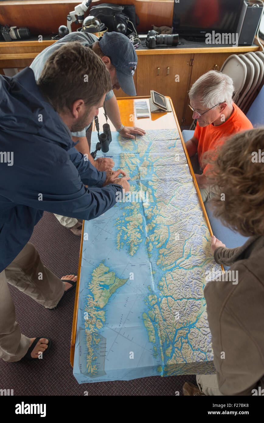 En regardant une carte de groupe sur un petit navire de croisière en Alaska. Banque D'Images