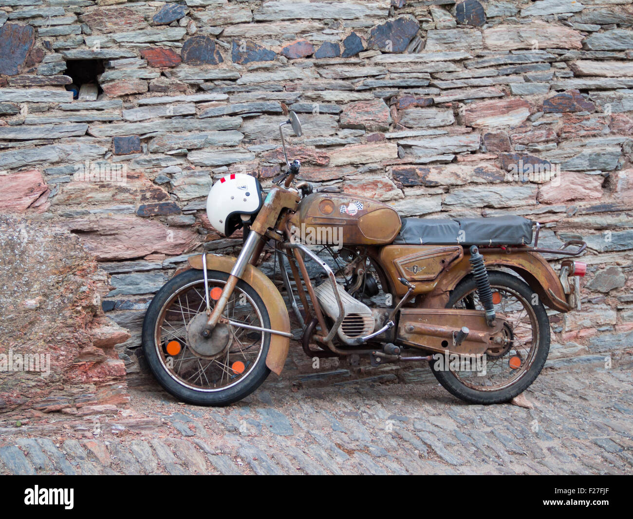 Vieille moto style appuyé contre un mur de pierre Banque D'Images