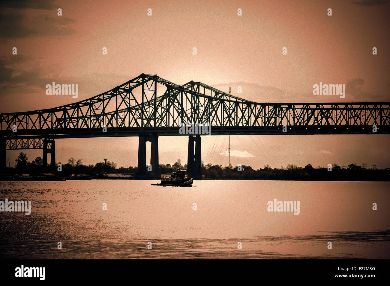 Un coucher de soleil sépia d'un bateau sur le fleuve Mississippi à la Nouvelle Orléans approche de la Crescent City Connection Bridge Banque D'Images