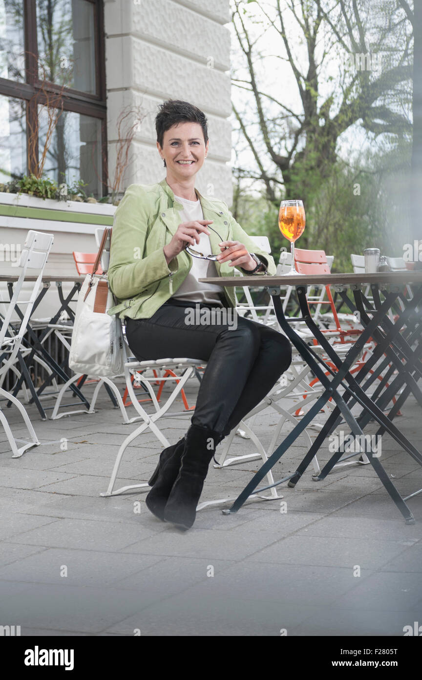 Femme mature aperol potable spritzat at sidewalk cafe, Bavière, Allemagne Banque D'Images