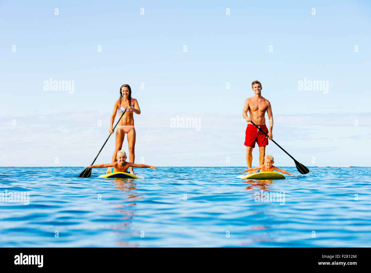 Family having fun Stand up Paddling ensemble dans l'océan le beau matin ensoleillé Banque D'Images