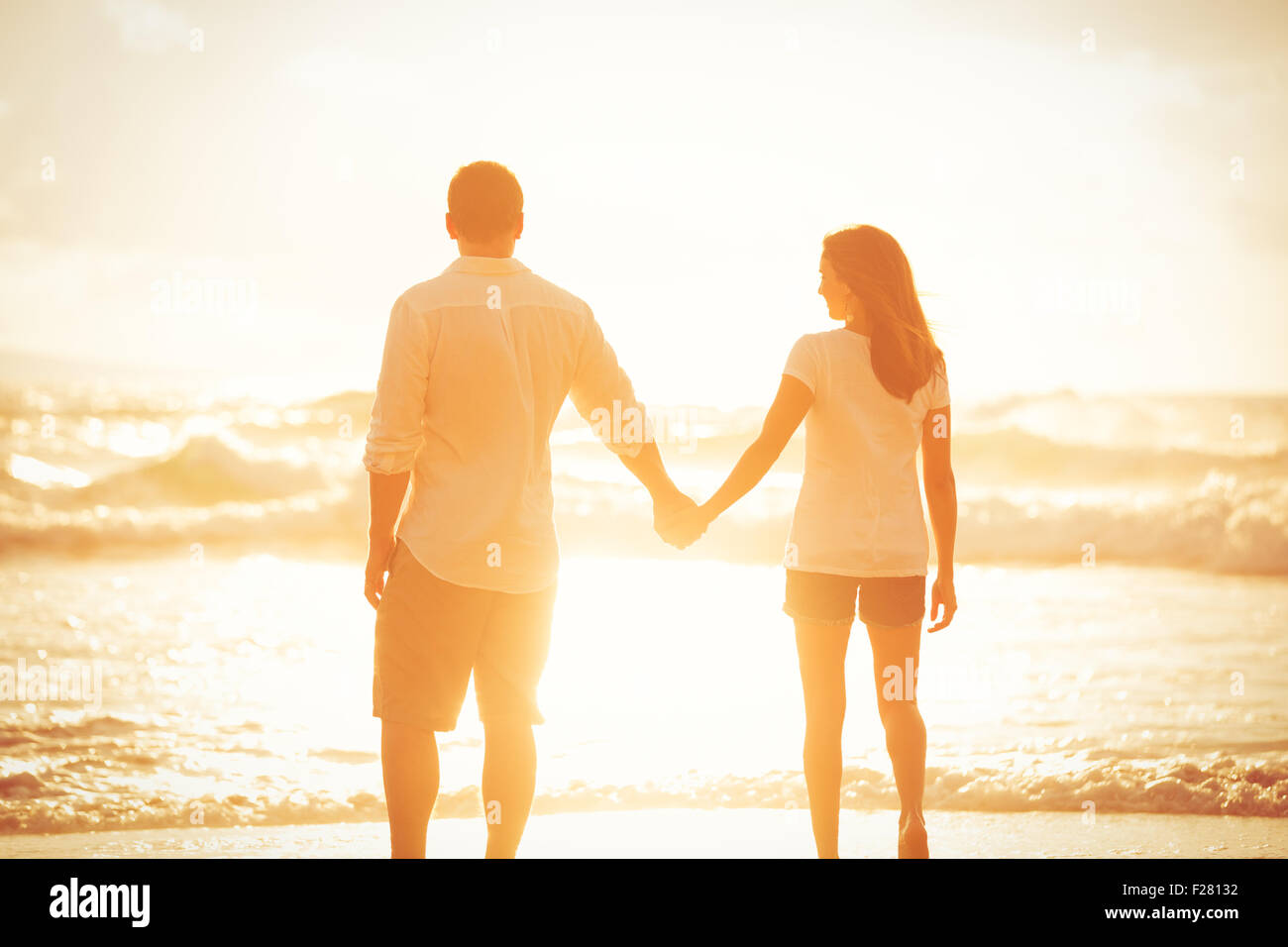 Happy Romantic couple en train de marcher sur la plage pour le coucher du soleil Banque D'Images