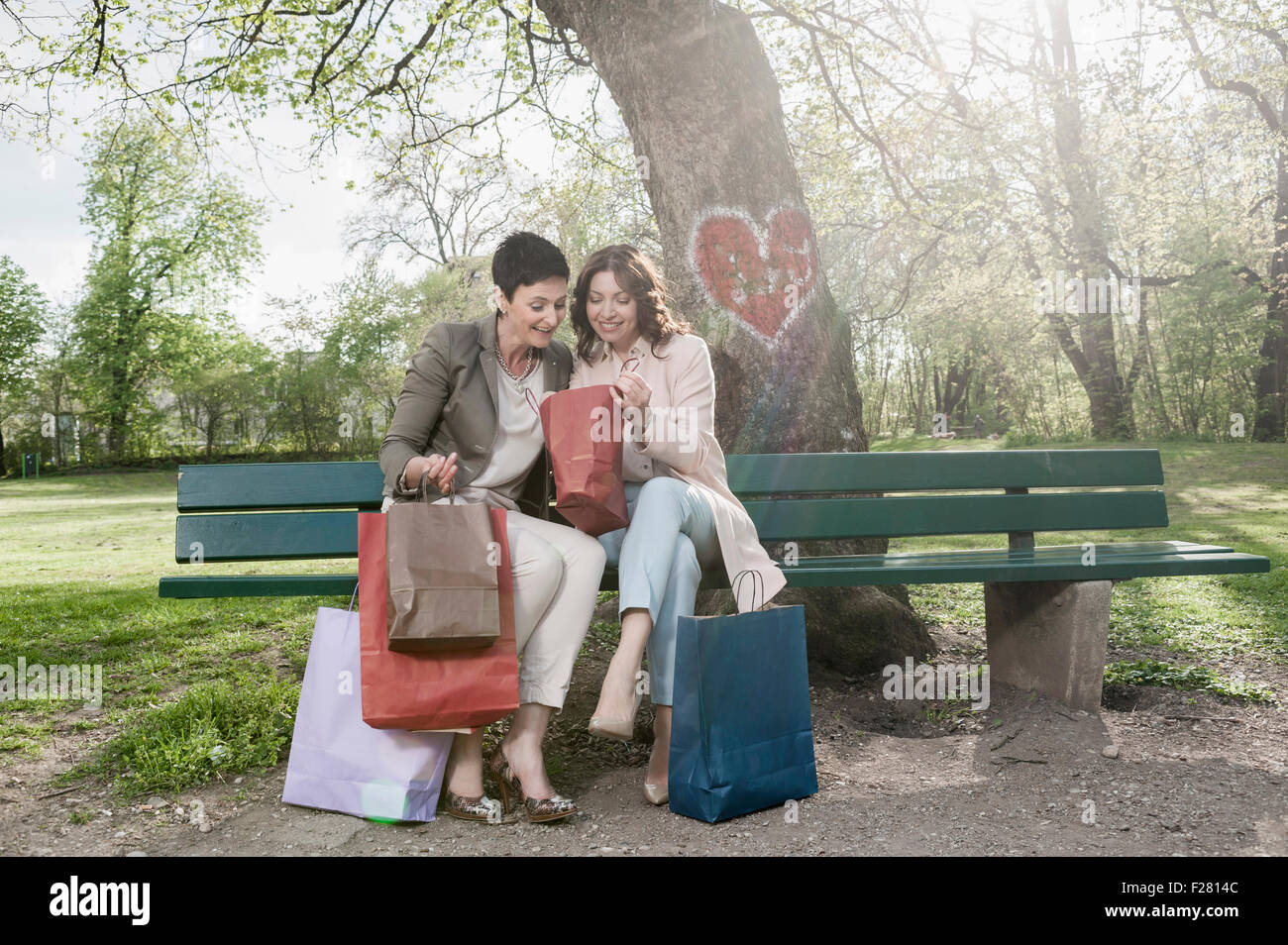 Deux femmes mûres à la recherche dans leurs sacs de magasinage, Bavière, Allemagne Banque D'Images