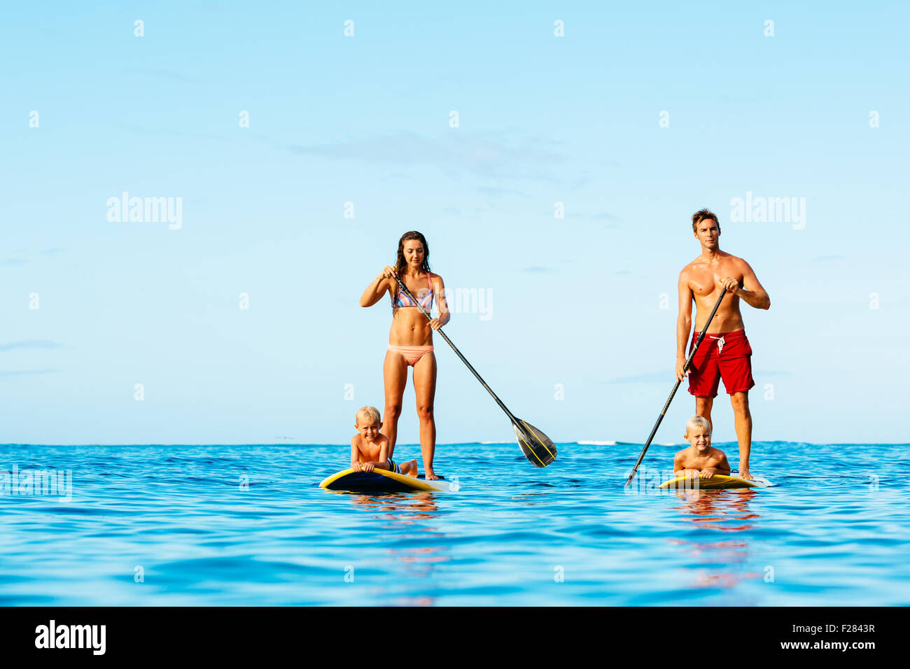 Family having fun Stand up Paddling ensemble dans l'océan le beau matin ensoleillé Banque D'Images