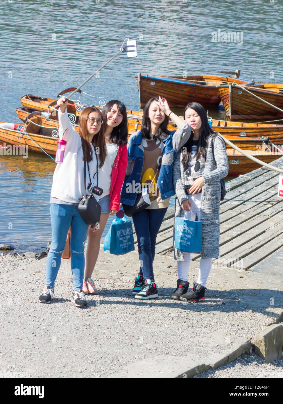 Un groupe de jeunes femmes asiatiques à l'aide d'un bâton pour se photographier selfies au lac Windermere Cumbria Banque D'Images