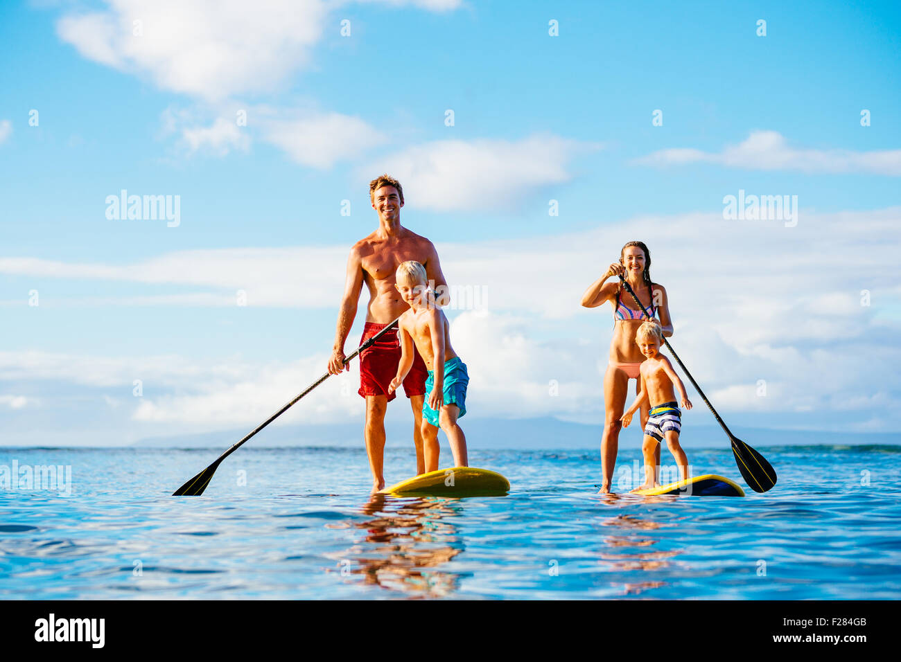 Family having fun Stand up Paddling ensemble dans l'océan le beau matin ensoleillé Banque D'Images