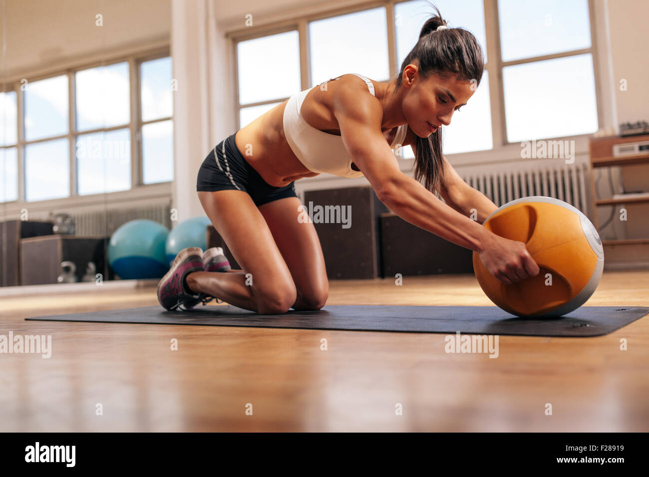 Strong woman d'entraînement intense avec kettlebell dans une salle de sport. Jeune femme faisant de l'exercice musculaire de base sur Tapis de fitness en guérir Banque D'Images