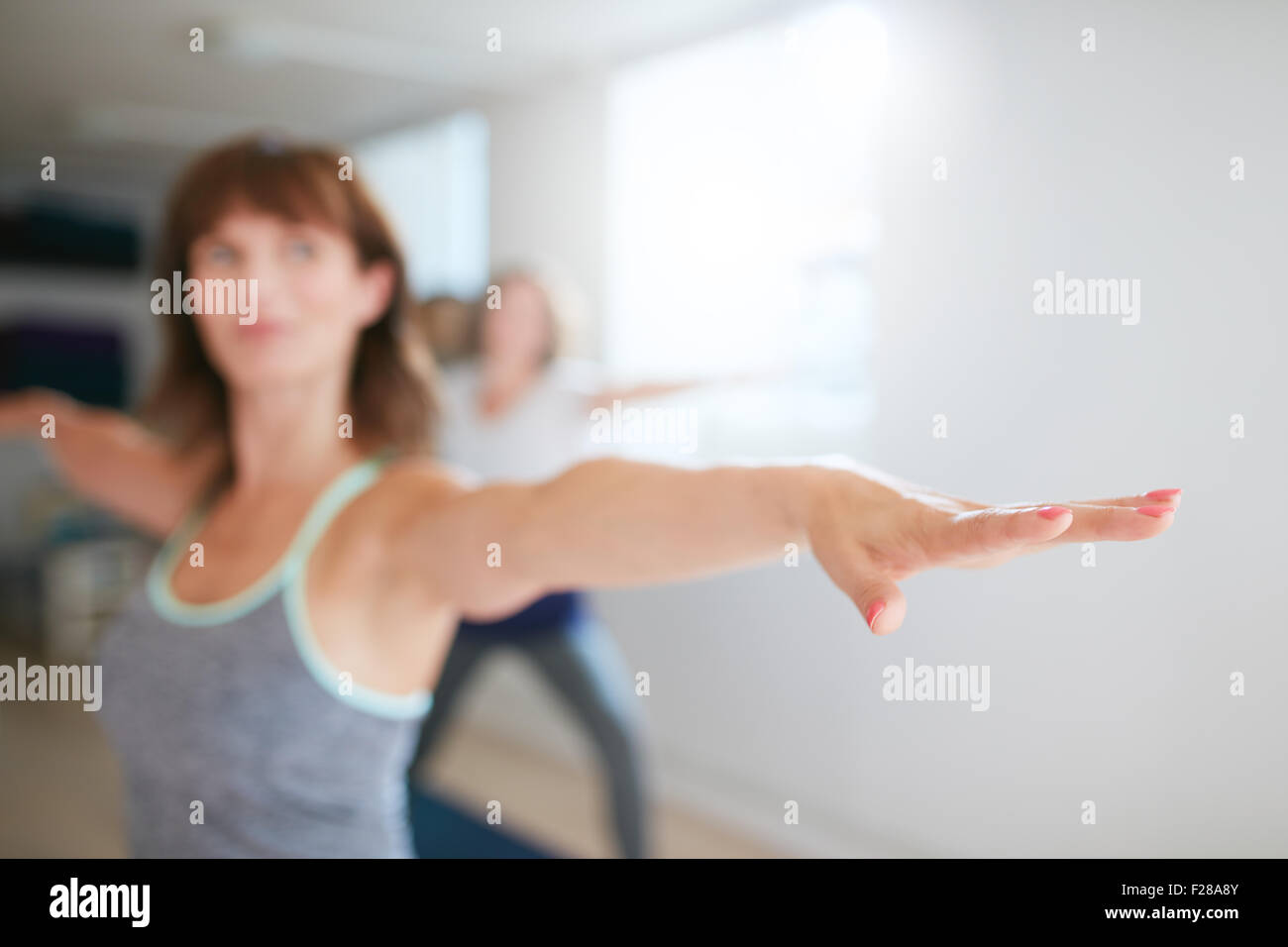 Femme étendant ses bras au cours de yoga. Fitness trainer dans warrior yoga pose. Virabhadrasana. Se concentrer sur la main. Banque D'Images