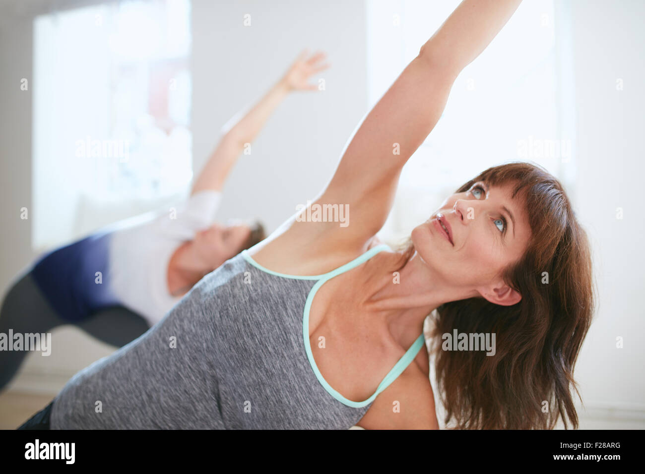 Portrait of young woman at gym. Femme de remise en forme Triangle faisant yoga pose, Trikonasana. Banque D'Images Portrait of young woman at gym. Femme de remise en forme Triangle faisant yoga pose, Trikonasana. Banque D'Images