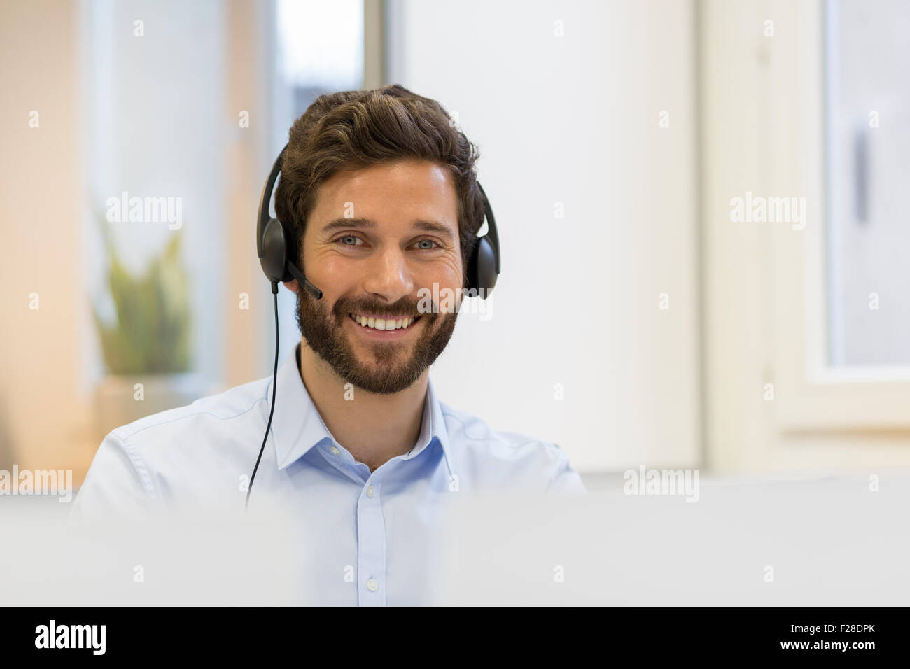 Portrait d'homme barbu avec casque au bureau Banque D'Images