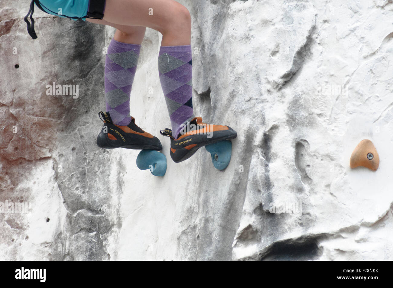 Young teen girl grimpe un mur d'escalade artificiel close up des pieds et des chaussures d'escalade Banque D'Images