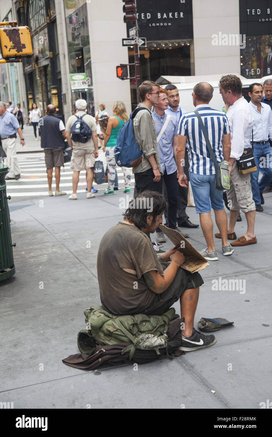 Sans-abri assis sur le trottoir et la mendicité parmi les touristes et les New-Yorkais à Midtown Manhattan. Banque D'Images