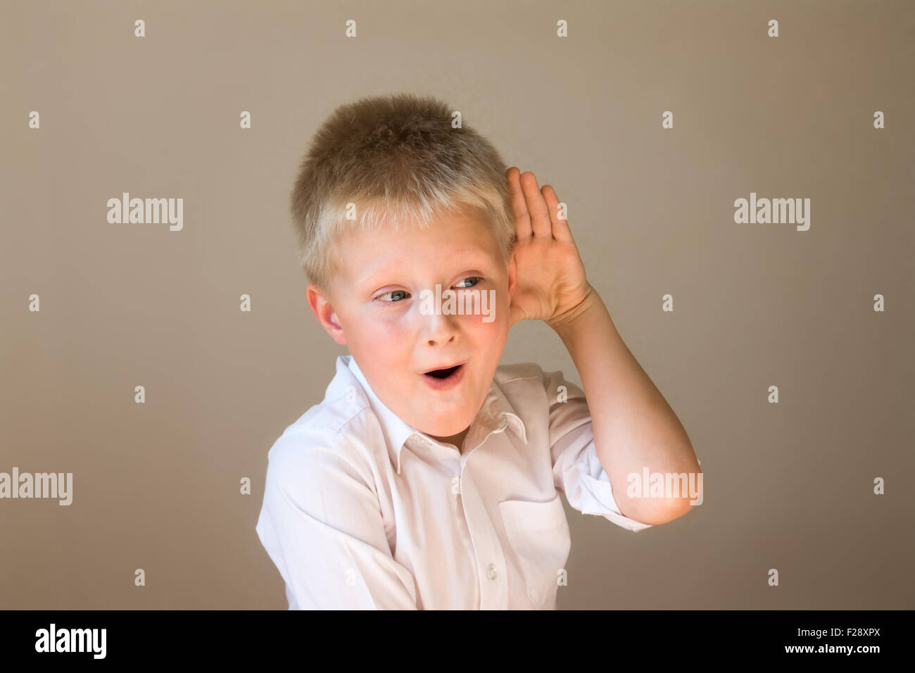 L'écoute de l'enfant drôle entendre quelque chose avec la main à l'autre concept Banque D'Images