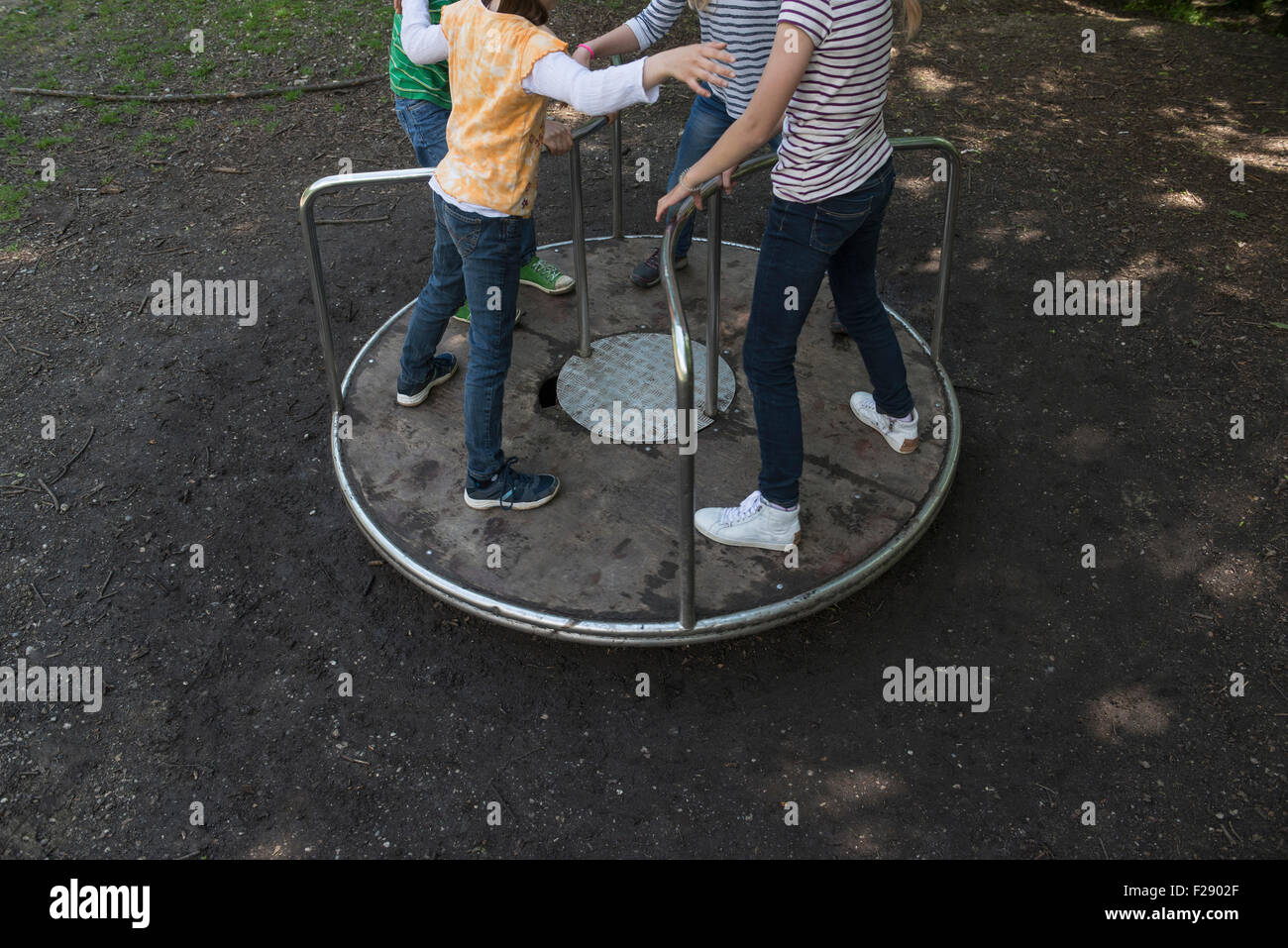 Les enfants s'amusant sur un carrousel en aire de jeux, Munich, Bavière, Allemagne Banque D'Images