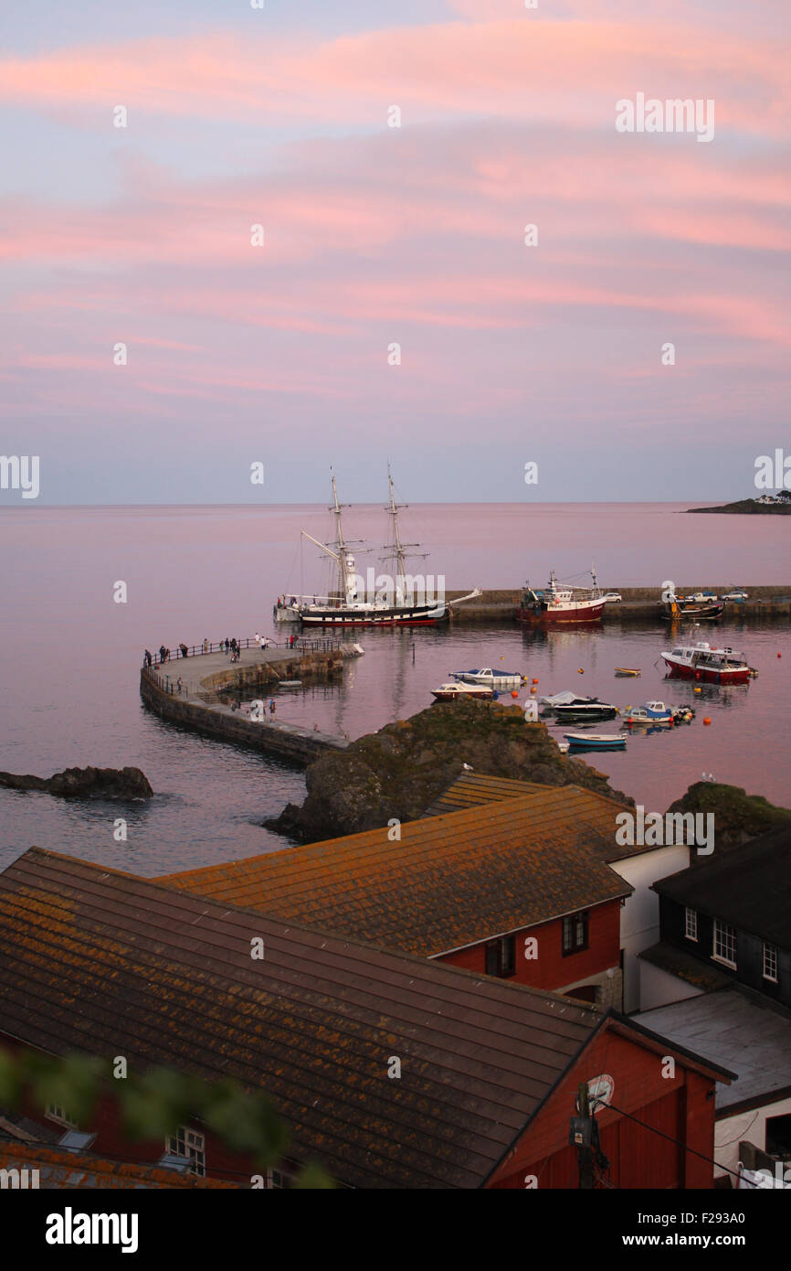 Mevagissey Harbour ci-dessous un soleil rose à Cornwall avec quelques bateaux de pêche amarrés et un zig zag menant à horizon Banque D'Images