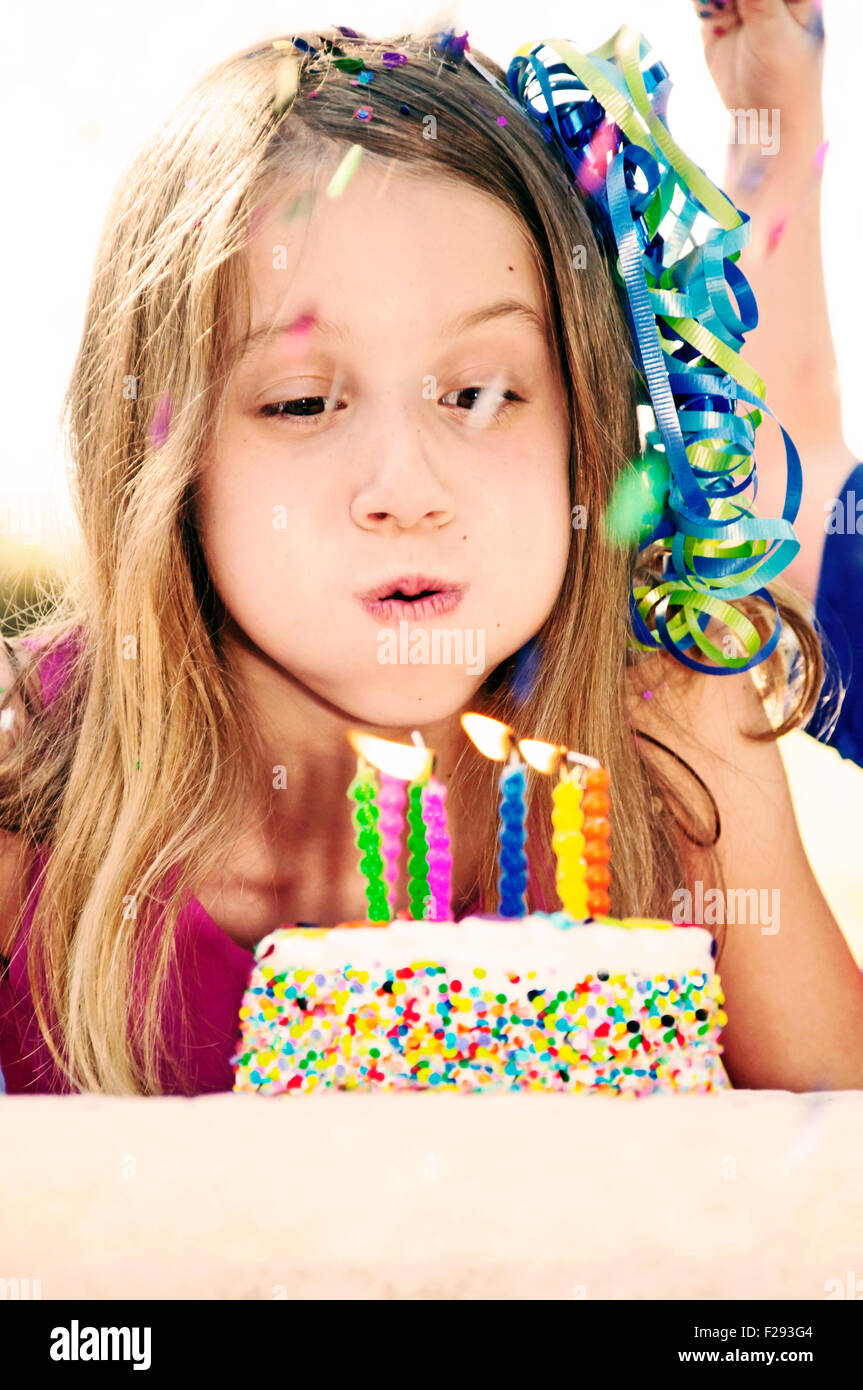 Birthday girl blowing out candles on cake Banque D'Images