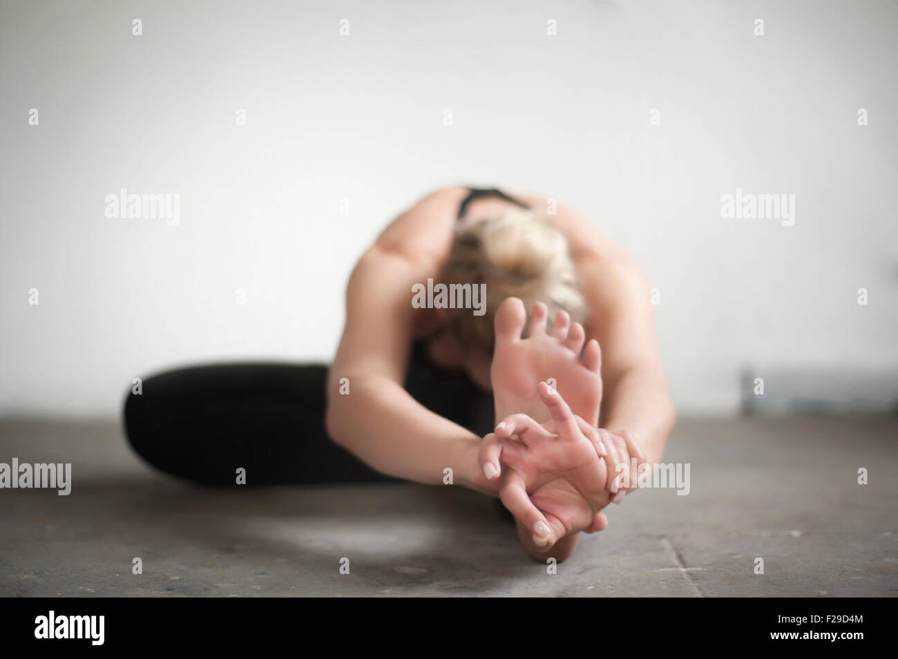 Mid adult woman practicing janu sirshasana poser dans un studio de yoga, Munich, Bavière, Allemagne Banque D'Images