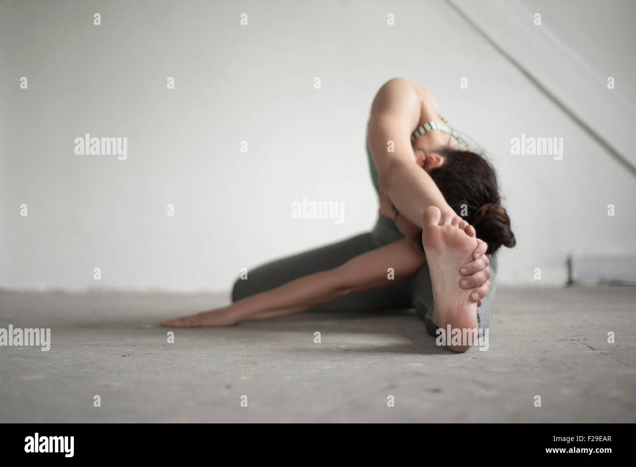 Mid adult woman practicing janu sirshasana poser dans un studio de yoga, Munich, Bavière, Allemagne Banque D'Images