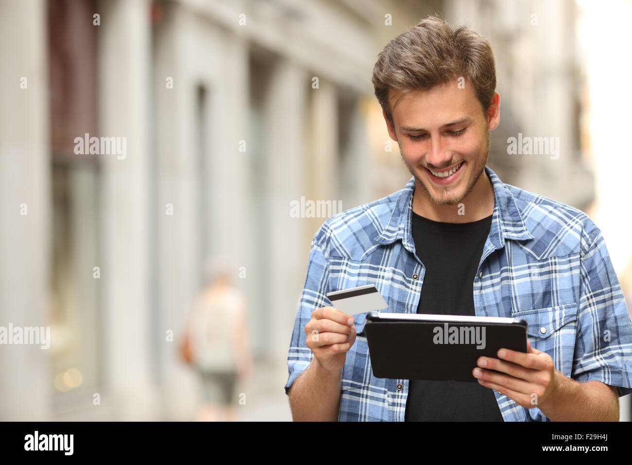 Jeune homme acheter en ligne avec une carte de crédit et une tablette dans la rue Banque D'Images