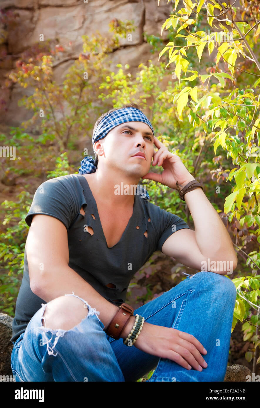 L'homme repose dans la nature assis sur une pierre dans la forêt d'automne Banque D'Images