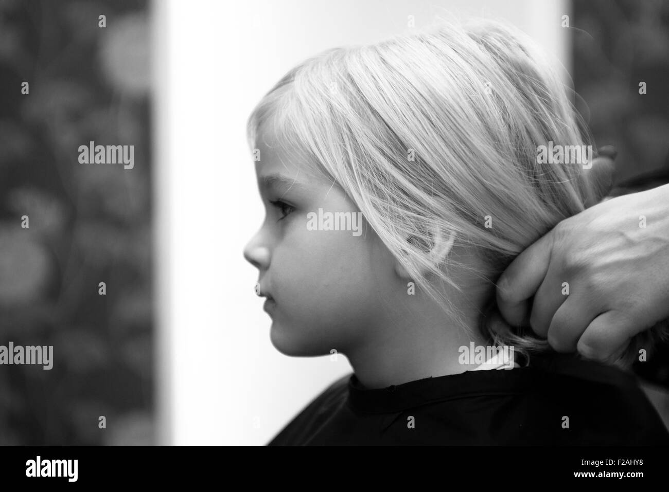 Coupe Coiffure féminine et le brossage du jeune enfant fille blonde cheveux dans le salon de coiffure Banque D'Images